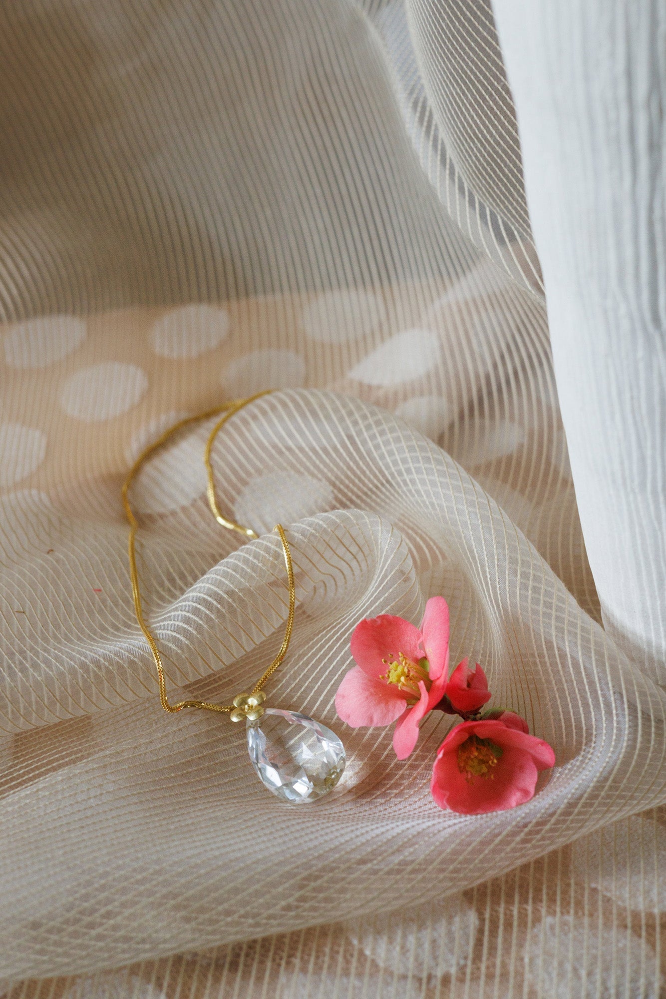 netted fabric with gold necklace and flowers draped on top.