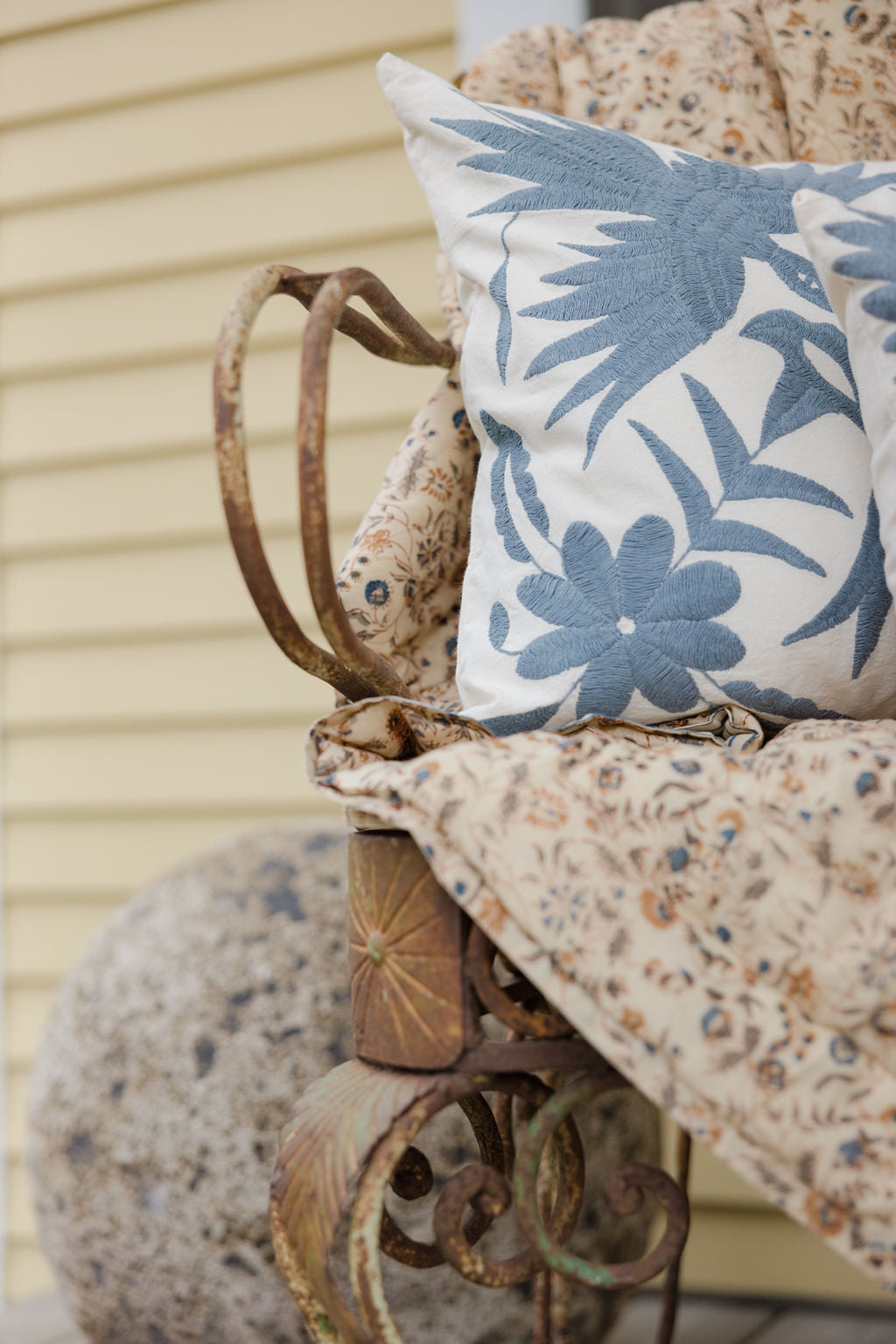 Decorative pillow with blue floral pattern on a rustic chair