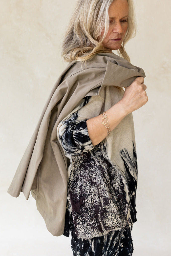 Woman wearing a beige scarf and patterned top against a plain background