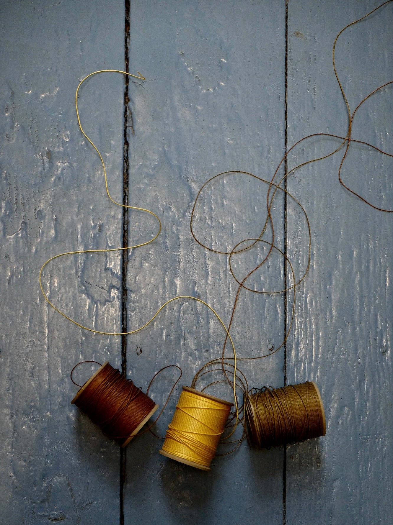 Three spools of thread on a textured wooden surface